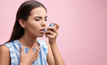 Woman holding asthma inhaler to her mouth 
